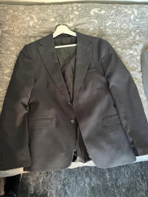 Mörkblå klassisk kavaj herr - Stilren mörkblå kavaj med två framfickor och en bröstficka. Klassisk passform med två knappar framtill och slits bak. Fodrad insida och diskreta knappar vid ärmslut. Perfekt för en dressad look.