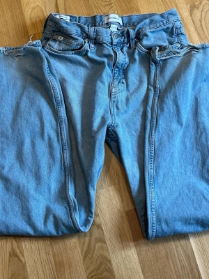 Ljusblå wide leg jeans Calvin Klein - Säljer ett par ljusblå jeans från Calvin Klein med breda ben och hög midja. Klassisk femficksmodell i mjuk denim med logotyppatch bak i midjan. Perfekta för en avslappnad och trendig look.  Pris är diskuterbart