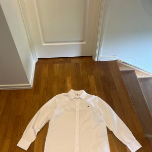 2 st Tommy Hilfiger skjortor strl 36 - Två klassiska skjortor från Tommy Hilfiger i storlek 36. En är vit och den andra ljusblå, båda med lång ärm, krage och knappar framtill. Diskret logga broderad på bröstet. Perfekt för en clean och stilren look. Tillverkade i bomull för skön känsla. En för 50 kr. Två för 100 kr