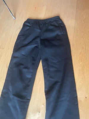 Svarta mjukisbyxor - Svarta mjukisbyxor med resår i midjan. Byxorna har sidfickor och är tillverkade i ett mjukt och bekvämt material, perfekt för en avslappnad stil. Enkla att matcha med olika tröjor och sneakers.