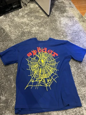 Spider t shirt - Cool blå t-shirt från Spider med stort gult spindelnäts-tryck och röd text på ryggen. Klassisk passform och korta ärmar, perfekt för dig som vill sticka ut. Riktigt go material. Använd 1 gång.