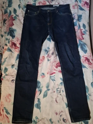 Mörkblå slim fit jeans - Snygga mörkblå slim fit jeans med klassisk femficksdesign och kontrastsömmar. Jeansen har raka ben och normal midja, perfekta för en stilren look. Passar till det mesta och är ett måste i garderoben. STL : W33 L34