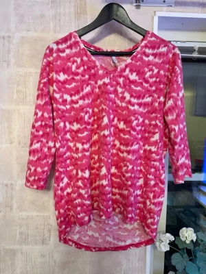 Blommig tröja  - Säljer en rosa och vit topp från Hays med v-ringning och trekvartsärm. Toppen har ett abstrakt mönster och är något längre baktill. 