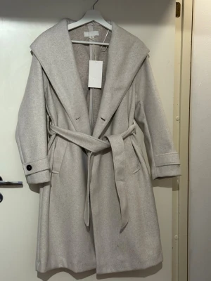Ljusbeige kappa med luva från Zara - Ljusbeige kappa med luva från Zara i storlek S aldrig använd med prislapp på fick den som present har två stycken vill sälja en av dem  köpt för 559 säljer den för 400kr nu 