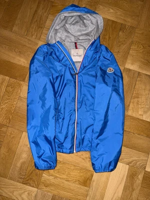 Moncler Windbreaker - Säljer en äkta ljusblå Moncler windbreaker i str 14a jag skulle säga att de passar de som är runt 152-164cm. Den är köpt på nk Göteborg för två år sedan och nypris var då runt 3799:- men nu ligger priset runt 4000:- . Nfc funkar såklart och jackan är i nyskick.