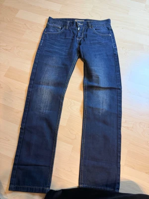 Mörkblå raka jeans från Lab Industries - Säljer ett par mörkblå jeans från Lab Industries med raka ben och klassisk femficksmodell. Jeansen har snygga slitningar framtill och kontrastsömmar. Tillverkade i slitstarkt denimtyg, perfekta för en avslappnad och trendig look.