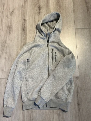 Ljusgrå zip hoodie från Sail racing  - Snygg ljusgrå hoodie från sail racing med dragkedja. Märkets logga broderad på bröstet. 