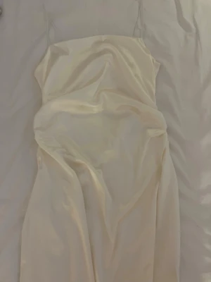 Champagnefärgad satinklänning med smala band - Säljer en elegant champagnefärgad långklänning i satin med tunna axelband och enkel, stilren design. Klänningen har en mjuk glans och faller snyggt längs kroppen. Perfekt för dig som vill ha en minimalistisk och chic look. 💞👚