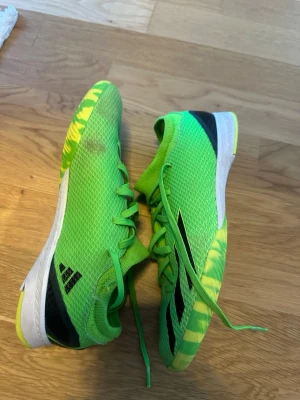 Gröna Adidas fotbollsskor - Säljer ett par grymt snygga fotbollsskor från Adidas i neon-grönt med svarta detaljer och vit sula. Ovandelen är i meshmaterial för bra ventilation och sulan har ett mönster i gult och grönt för extra grepp på planen. Perfekta för dig som vill sticka ut på fotbollsplanen!
