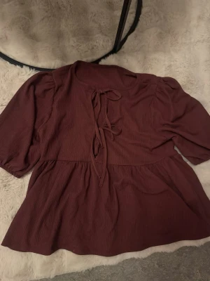 Röd blus med knyt och puffärm -  röd blus med knyt framtill och lätt puffade ärmar. 