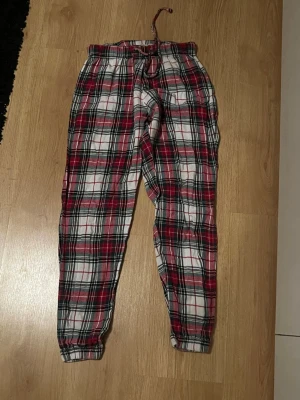 pyjamasbyxor från Cubus - Barnstorlek S från cubus. Mysiga pyjamasbyxor med klassiskt rutigt mönster i rött, vitt och svart. Byxorna har resår i midjan. Perfekta för chillkvällar hemma. Tillverkade i mjukt bomullstyg. 