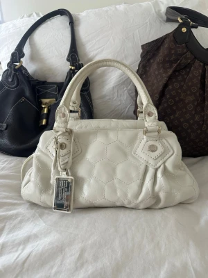 Så söt vit Q Classic Baby Groove! - Så fin handväska i äkta läder från Marc by Marc Jacobs. Den populära modellen Q Classic Baby Groove! En eftertraktad vintagemodell med silverdetaljer och dubbla handtag. Långa bandet finns! Skick enligt bilder, helhetsintrycket är väldigt bra men mindre tecken på användning finns 🤍  Mått: 34x18x12 cm (undersida) Kan hämtas hemma hos mig i Nacka eller skickas! Skriv privat för fler bilder!🤍 