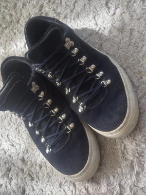 Diemme skor stl 44 - Snygga mörkblå sneakers i mocka med vita sulor och coola metallhakar för snörningen. Skorna har en låg profil och mörkblå skosnören som matchar ovandelen. Perfekta för dig som gillar en stilren men ändå unik look.