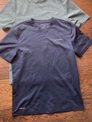 Två Endurance trängins t-shirts  - Säljer två stilrena t-shirts från ENDURANCE, en i mörkblå och en i grön nyans. Båda har diskret logga på bröstet och texten 'QUICK DRY' vid nederkanten. Klassisk passform med korta ärmar och rund hals. Perfekta för träning eller chill dagar.