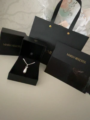 Maria Nilsdotter ”pearl tear” halsband - Snyggt halsband i silver med en droppformad vit pärla som hänge från Maria Nilsdotter. Kedjan är tunn och har en klassisk design. Perfekt för dig som gillar stilrena accessoarer med en elegant touch. Halsbandet är köpt i maj 2025, det är sparsamt använt och i väldigt väldigt bra skick. Kedjan är i längden 45.  Köpt för 2595kr. Priset kan eventuellt vara diskuterbart! Tveka inte att höra av er om ni undrar något eller vill ha fler bilder på det!☺️💕