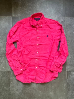 Ralph lauren linne skjorta  - Tjena, säljer nu denna riktigt snygga och populära Ralph lauren linneskjortan i färgen rosa med mörkblått Ralph lauren märke, den ät storlek S slim fit och passar bra på mig som är 180 och väger 65 cm, den är i bra skick, ända saken är att tagsen inuti är bortklippta, hör av er vid frågor och funderingar🙌🤝 