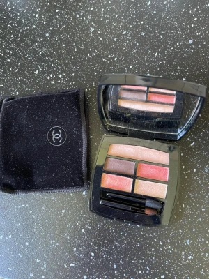 Chanel Les Beiges ögonskuggspalett - Snygg ögonskuggspalett från Chanel Les Beiges med fem nyanser i varma toner som beige, rosa, brun och guld. Kommer i en elegant svart dosa med spegel och tillhörande borste samt en svart sammetsfodral med Chanel-logga.