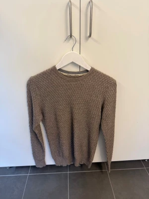 Beige stickad tröja i 100% extra fin Merinoull från Stenströms, stl M  - Säljer en beige stickad tröja i storlek M med snyggt strukturmönster från Stenströms. Tröjan har rund halsringning, långa ärmar och ribbade muddar. Perfekt för lager på lager och enkel att matcha med olika outfits. Tröjan är gjord i 100% extra fin Merinoull.