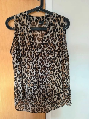 Leopardmönstrad ärmlös topp - Snygg ärmlös topp med leopardmönster. Toppen har v-ringning och är tillverkad i ett lätt och luftigt material, perfekt för varma dagar.