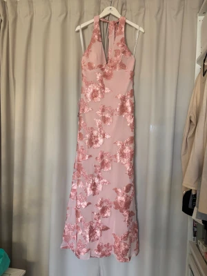 Lång rosa klänning med blommig spets - Pris kan diskuteras vid snabbt och smidigt köp! Superfin långklänning i ljusrosa med blommiga spetsdetaljer i glansigt tyg. Klänningen har halterneck och djup v-ringning framtill. Perfekt för speciella tillfällen när du vill sticka ut lite extra. Skriv om ni har frågor eller vill ha fler bilder🌸