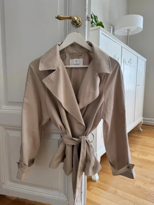 Trenchcoat - Ljusbeige trenchcoat med knytning
