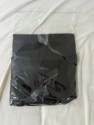 Svart t-shirt från Tommy Hilfiger - Klassisk svart t-shirt från Tommy Hilfiger med rund hals och diskret logga på bröstet. Tillverkad i mjuk bomull och har korta ärmar. Perfekt basplagg för en clean och stilren look.