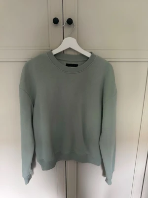 Ljusgrön sweatshirt från 157 - En stilren ljusgrön sweatshirt från 157 i storlek XS. Tröjan har rund halsringning, ribbade muddar vid ärmslut och nederkant samt en mjuk insida. Tröjan är lite oversized 