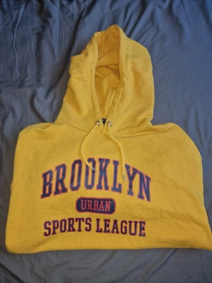 Gul hoodie med Brooklyn-tryck - Oversized passform och perfekt för en sportig och avslappnad stil.
