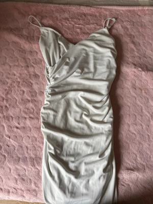 Vit omlottklänning från Zara - Snygg vit omlottklänning från Zara i mjukt material. Klänningen har en draperad effekt och knytning i midjan som ger en fin siluett. Perfekt för dig som gillar stilrena och trendiga plagg.