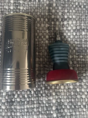 Jean Paul Gaultier Le Male parfym - Jean Paul Gaultier Le Male parfym i den ikoniska blå-randiga flaskan formad som en manlig torso. Flaskan står på en röd bas och kommer med original metallburk. Perfekt för dig som gillar unika och snygga parfymflaskor. (Sprillans ny)!