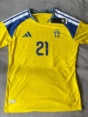 Sverige Kulusevski 21  - Sjukt clean Sverige-tröja med Dejan Kulusevski tryck på ryggen 🔥 Den gula färgen tillsammans med blå detaljerna gör den riktigt brutal irl.  • Sverige landslag • Kulusevski #21 • Storle M (L men passar som M) • Climacool • Ny med tags • Snygga detaljer & premiumkänsla • Perfekt till match, outfit eller samling  En riktigt tung tröja för alla Sverige-fans 🇸🇪  💰 Pris: 449kr 📍 skickas  