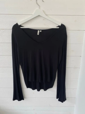 Svart v-ringad topp  - En svart långärmad topp från NLY Trend med v-ringning och figurnära passform. Tunt och mjukt material som sitter snyggt på kroppen. Perfekt att styla med jeans eller kjol för en trendig look.