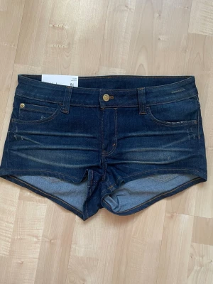 Mörkblå jeansshorts med dragkedja - Snygga mörkblå jeansshorts med klassisk femficksdesign, gylf med dragkedja och knapp framtill. Shortsen har en lätt tvättad look och är perfekta för varma dagar. Passar dig som gillar en enkel och stilren denimstil. Nya med prislapp kvar