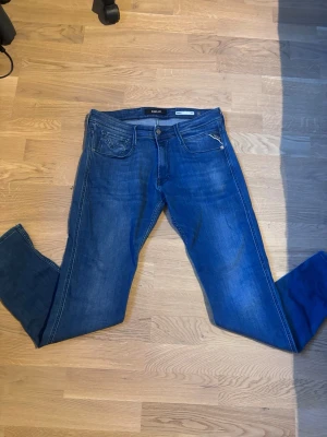 Blå slim fit jeans från Replay (Anbass) W33 L32 - Säljer ett par klassiska blå slim fit jeans från Replay. Jeansen har fem fickor, dragkedja och knapp framtill samt snygga detaljer på bakfickorna. Tillverkade i mjuk denim med lätt tvättad look. Dem e knappt använda och är lite mindre i storleken och riktigt sköna. Perfekta jeans inför sommaren W33 L32