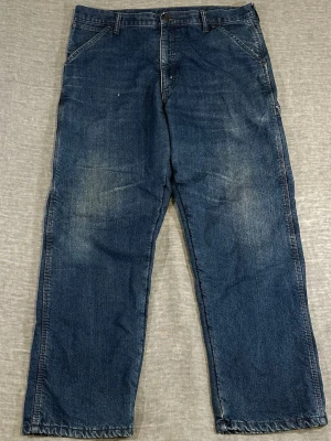 Vintage 2000’s Wrangler Lined Carpenter Jeans 38x32 Baggy Workwear Denim - Vintage 2000’s Wrangler lined carpenter jeans with warm fleece-style interior lining throughout. Heavyweight workwear denim with utility pocket details, hammer loop, and a great oversized baggy fit. Medium blue wash with natural fading and wear. Perfect colder weather workwear/streetwear pair with strong rugged Americana vibes. Tagged 38x32 and fits true to size relaxed.  Measurements: Waist 49 cm, Thigh 36 cm, Foot 33.5 cm, Length 106 cm.