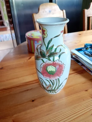 Vit porslinsvas med blommönster - Säljer en elegant vit porslinsvas med handmålat blommönster i grönt, rosa och gult. Vasen har en klassisk form med smal hals och vid öppning, perfekt som dekoration eller för snittblommor. Passar fint på bord eller hylla.