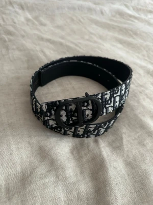 Bälte med monogram - Snyggt bälte  med svart och vitt monogrammönster och en stilren svart spänne. Perfekt accessoar för att lyfta din outfit med en lyxig touch. Bältet är i textilmaterial och har en klassisk form. 100cm.