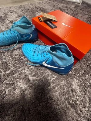 Nike phantom luna ll fotbollsskor  - Användt i 3veckor bara på konstgräs nu under vintern och är knappt använda som man ser på innesulan. Väldigt bra formen på skon och extremt bra grepp. Inte gått på grus eller något med dem så minimalt slitning på undersidan. De svarta som syns få skorna går lätt bort i tvätten men använde dem 1 gång efter jag tvättade dem senast därför de svarta dammet på dem. Kan givetvis tvätta dem innan jag skickar.