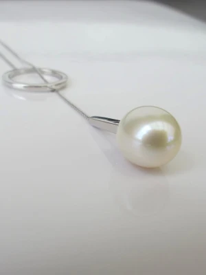 Äkta Pärlhalsband i Silver - Stilrent halsband i silver med en rund vit äkta pärla som hänge. Kedjan är tunn och har en cirkelformad detalj i silver som ger en modern touch. Perfekt för dig som gillar minimalistiska smycken med en elegant känsla.