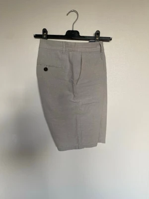 Beige shorts  - Herrshorts i linneblandning i beige färg, storlek 31.Klassisk modell. Material enligt lapp: linne och bomull. Passar som vardags- eller sommarshorts.