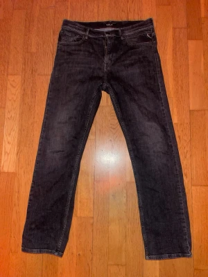 Svarta raka jeans från Replay - Säljer ett par svarta jeans från Replay med rak passform och klassisk femficksdesign. Jeansen är tillverkade i bomullsdenim med lite stretch för extra komfort. Perfekta för en avslappnad och stilren look. Passar för en kille som är 158 cm lång ungefär. 