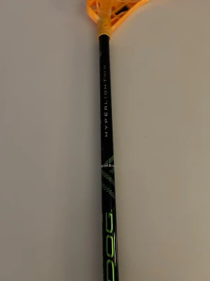 Oxdog Hyperlight innebandyklubba - Säljer en oxdog Hyperlight innebandyklubba med svart skaft och orange blad. Skaftet har detaljer i grönt och texten 'Hyperlight'. Greppet är vitt och klubban är lätt och smidig. Har inga slag på sig alls och är typ ny, använd några gånger. Nypris 1800. 98 cm lång. 