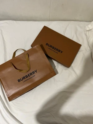 Mörkblå rutig halsduk från Burberry - Snygg mörkblå halsduk från Burberry i klassiskt rutigt mönster med röda och ljusblå detaljer. Halsduken har fransar i ändarna och är tillverkad i mjuk ull. Perfekt accessoar för att lyfta din outfit med en tidlös och lyxig känsla.