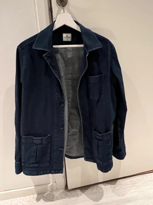 Mörkblå overshirt i bomull - Stilren mörkblå overshirt med klassisk krage och tre fickor framtill. Tillverkad i mjuk bomull och har knäppning framtill. Perfekt att slänga över en t-shirt för en avslappnad look. Från John Henric 