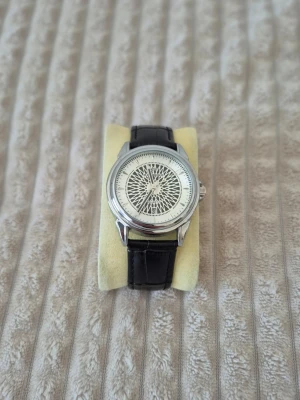 Stainless steel silver klocka med läderband - Snygg klocka med unikt mönstrad vit urtavla och silver boett. Klockan har ett svart läderband med krokodilmönster och klassiskt spänne. Perfekt accessoar för dig som gillar stilrena detaljer och modern design.