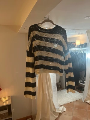 Randig stickad tröja i blå och vitt - Säljer en cool stickad tröja med breda blå och vita ränder. Tröjan har en luftig, hålig stickning och avslappnad passform med långa ärmar och rund hals. Perfekt för lager på lager och en chill look.