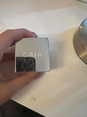 CAIA Wake Me Up Powder Rhubarb - Säljer ett CAIA Wake Me Up Powder i nyansen Rhubarb. Pudret kommer i en snygg, fyrkantig silverfärgad förpackning med spegeleffekt och tydlig logga på locket. Perfekt för att fixera sminket och ge en fräsch finish.