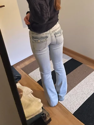 Ljusblå bootcut jeans, low waisted  - Säljer ett par ljusblå bootcut jeans med snygga fickdetaljer både fram och bak. Jeansen har låg midja och klassisk femficksdesign. Skicka om du har någon fråga?💕