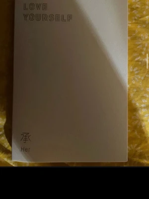 LOVE YOURSELF Her av BTS - LOVE YOURSELF Her är en bok med vit pärm och minimalistisk design från BTS. Omslaget har text i svart och koreanska tecken. Perfekt för dig som gillar K-pop och vill ha något snyggt i bokhyllan.
