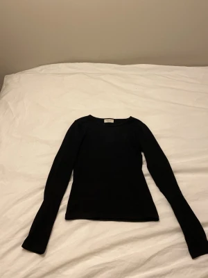 Svart långärmad tröja Gina Tricot - En svart, figurnära långärmad tröja från Gina Tricot, kollektionen Basically Basics. Tröjan har rund halsringning och är tillverkad i ett mjukt, stretchigt material som passar perfekt till lager-på-lager-stil.